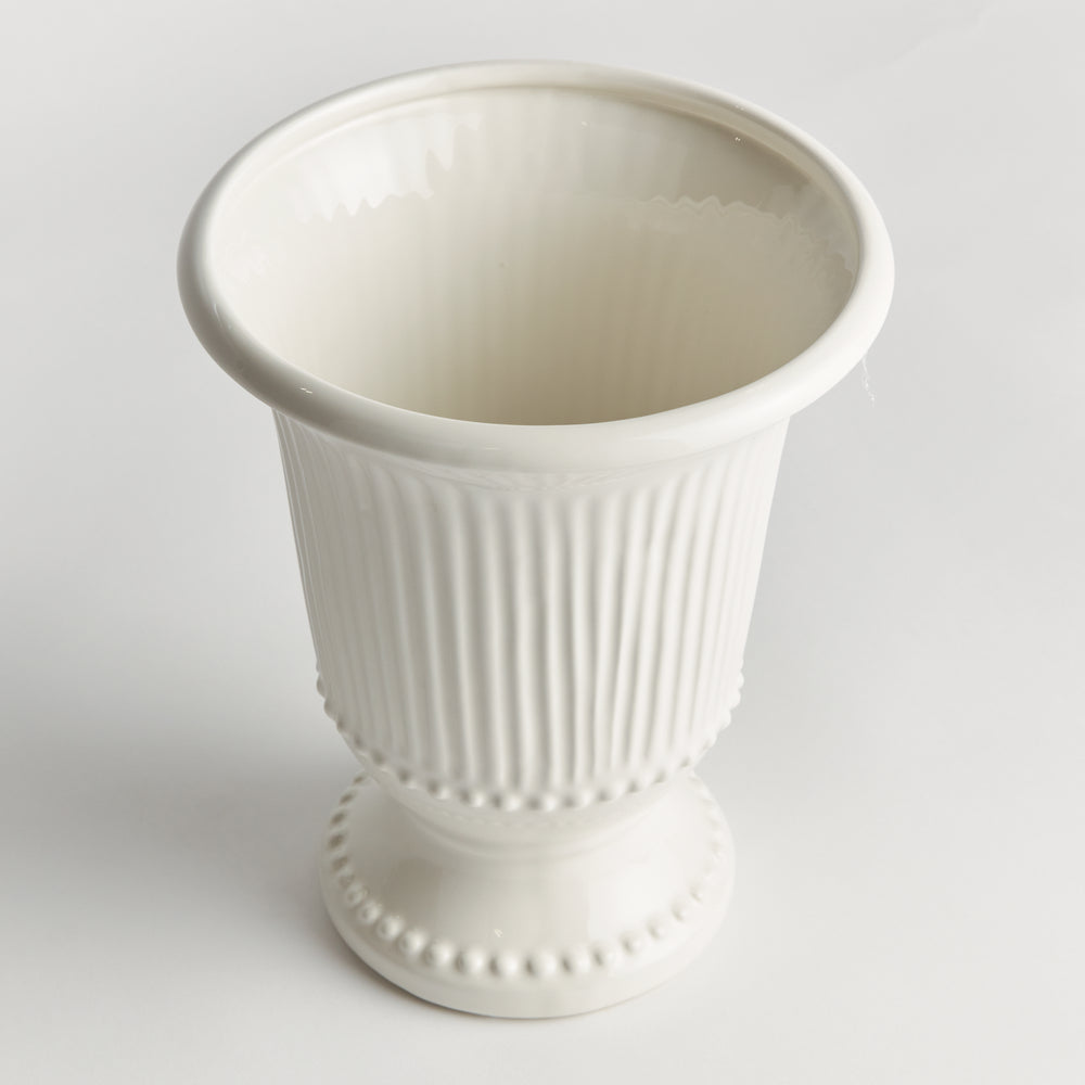Angled view of a white fluted clay vase showing its open rim, rounded beading and decorative pedestal foot | Traditional