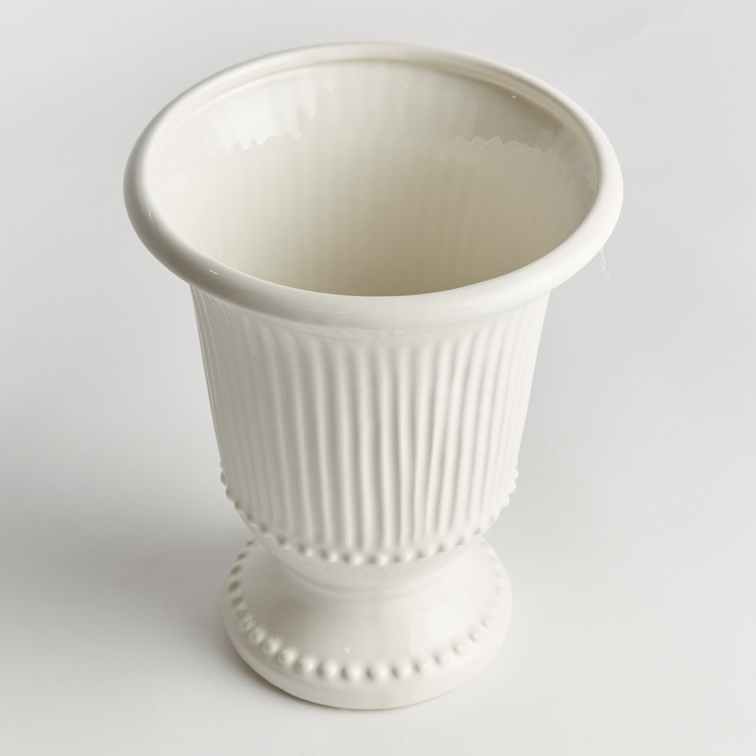 Angled view of a white fluted clay vase showing its open rim, rounded beading and decorative pedestal foot | Traditional