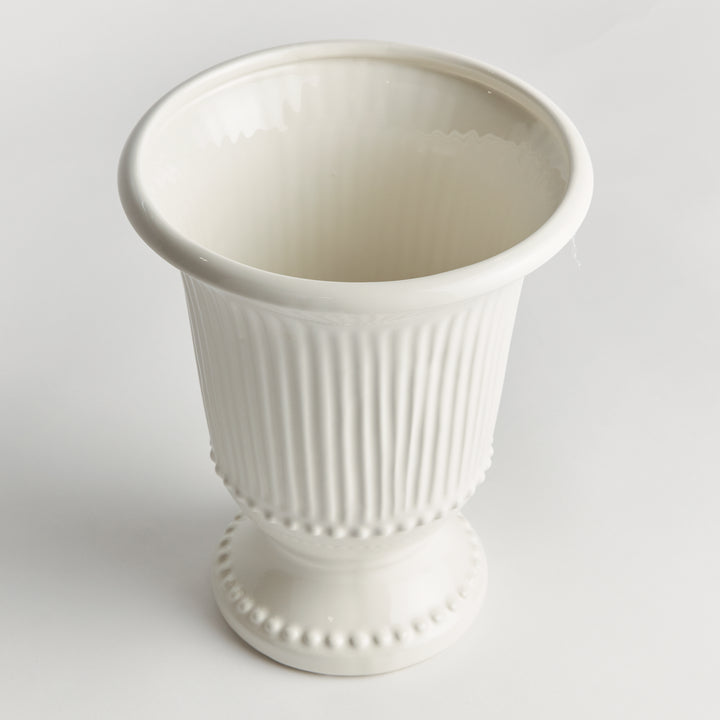 Angled view of a white fluted clay vase showing its open rim, rounded beading and decorative pedestal foot | Traditional