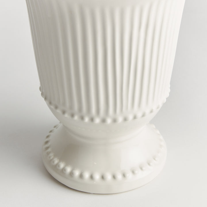 Detail of vertical fluting and raised beaded trim on a white clay vase, with the pedestal base also in view | Traditional