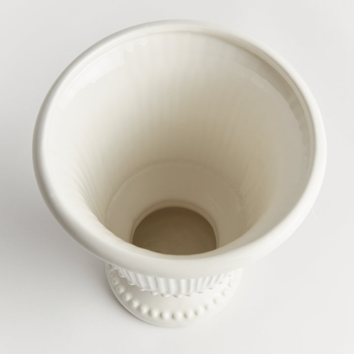 Top view into a white fluted clay pedestal vase, showing the circular opening, pale interior and shaped rim | Traditional