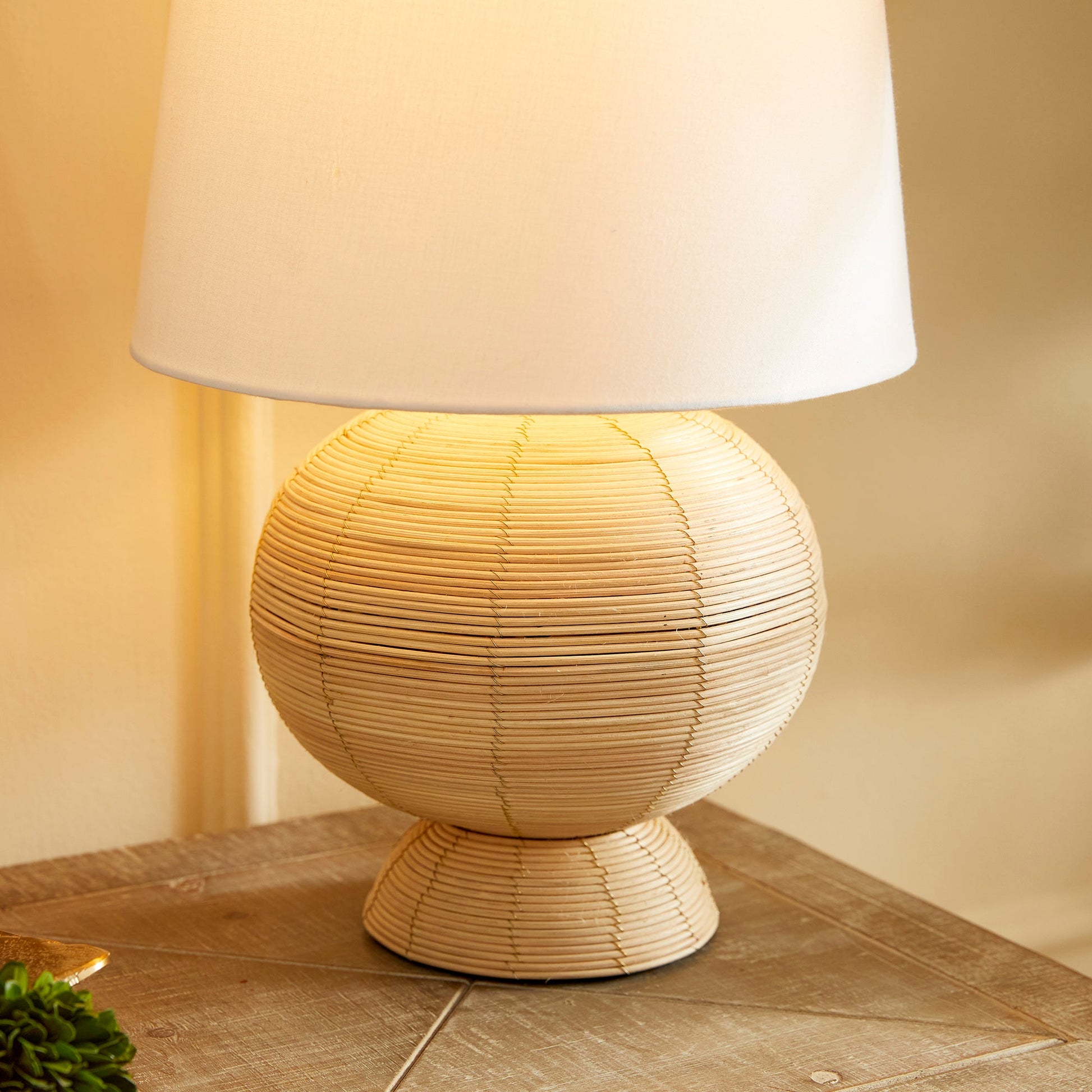 Handcrafted from whitewashed cane rattan, each hourglass table lamp features a distinctive color variation, making it truly one-of-a-kind. Its wide cylindrical white shade adds the perfect touch to any bedroom, living room, or study, solidifying its status as a timeless accent piece.