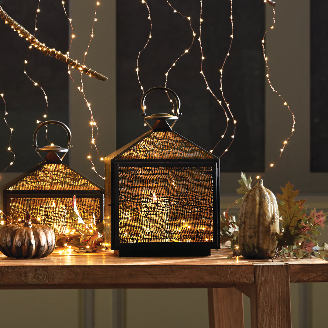 The Amhurst Indoor Lantern Medium boasts an intricate mesh pattern that diffuses candlelight with expert precision. Its golden brass interior adds a touch of elegance to the warm glow, making it a stunning addition to any indoor area.