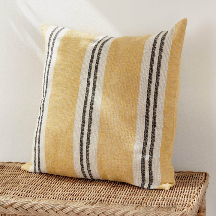 Lifestyle: 24-inch flax linen striped pillow in ochre and charcoal on wicker chair, natural woven texture – Modern Boho.