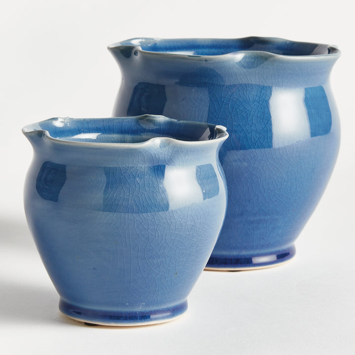 Blue ceramic pot pair shown at an angle, with ruffled rims, rounded bodies and a reflective reactive glaze. Transitional
