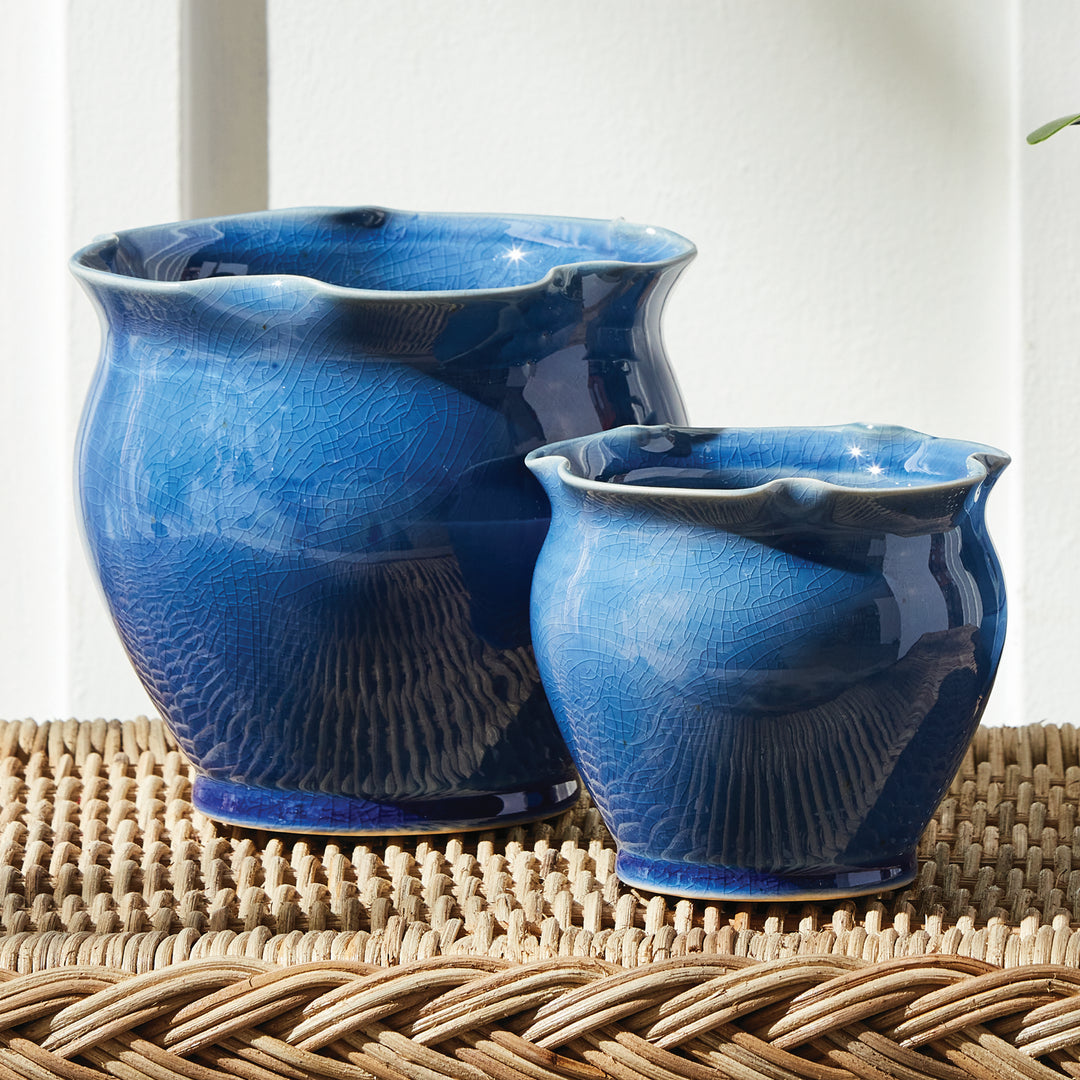 Blue ceramic planter set styled on a woven surface, showing rounded bodies and softly ruffled rims. Classic Transitional