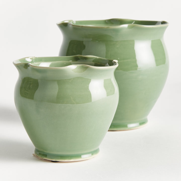 Green ceramic pot pair shown at an angle, with ruffled rims, rounded bodies and a reflective reactive glaze. Transitional