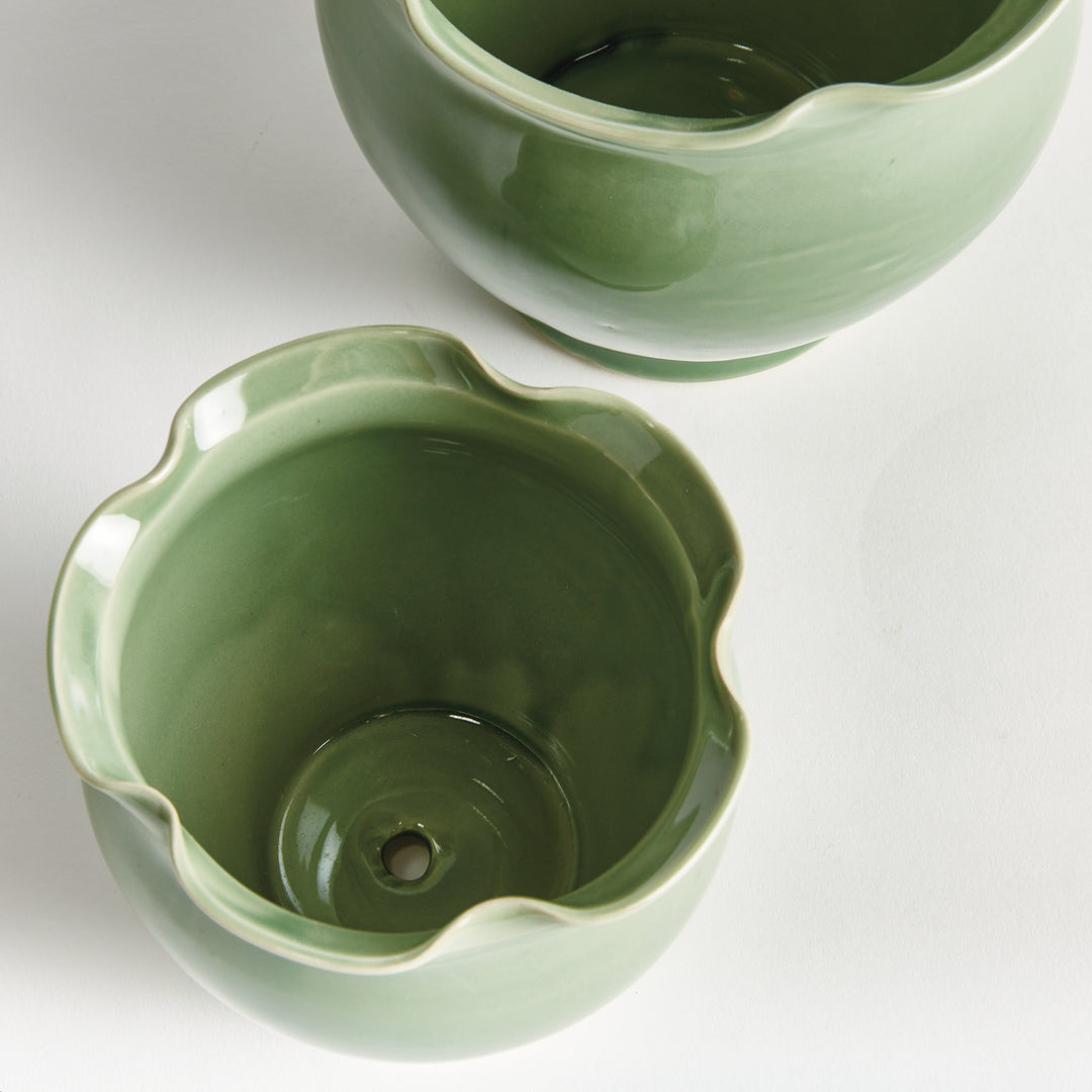 Green ceramic planter pair viewed from above, showing the glazed interiors, wavy rims and drainage hole. Classic Transitional