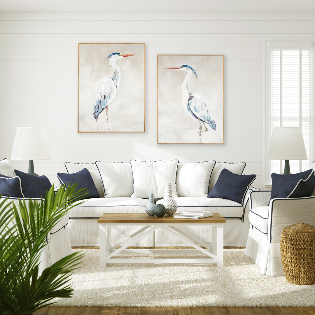 Framed heron canvas giclee prints styled above a pale sofa in a light living room with blue cushions, Coastal Transitional
