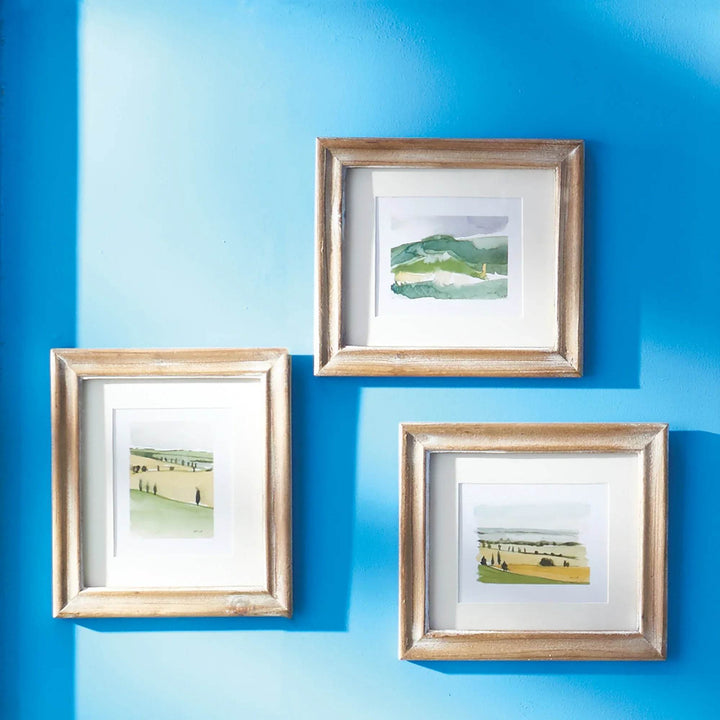 Set of three framed Italian landscape prints by Whitney Wolf on bright blue wall, watercolor countryside art for gallery styling – Modern Traditional.

