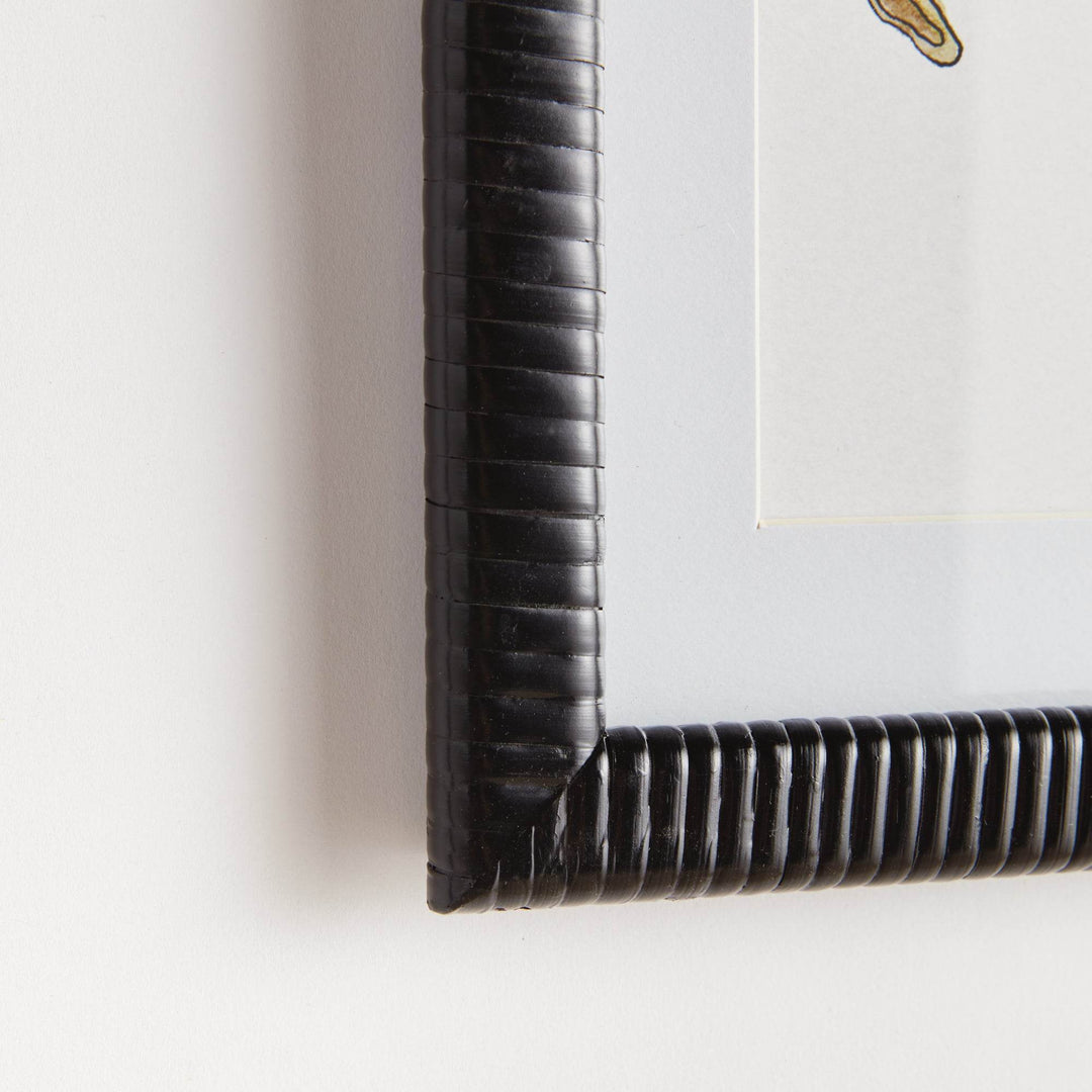 Close-up of rattan-wrapped black frame corner detail on fruit botanical wall art print with glass cover and white matting.