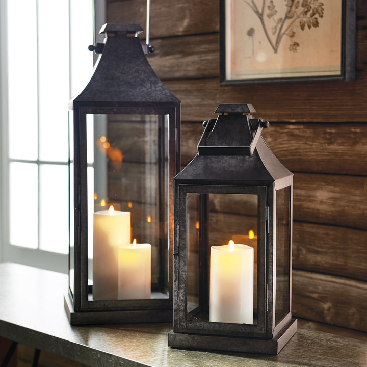 Pair of galvanized metal lanterns styled with pillar candles on console table for architectural decor style