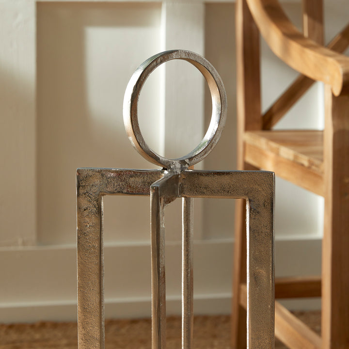 Close view of antique silver geometric metal lantern ring handle and textured frame with warm wood background, Transitional style
