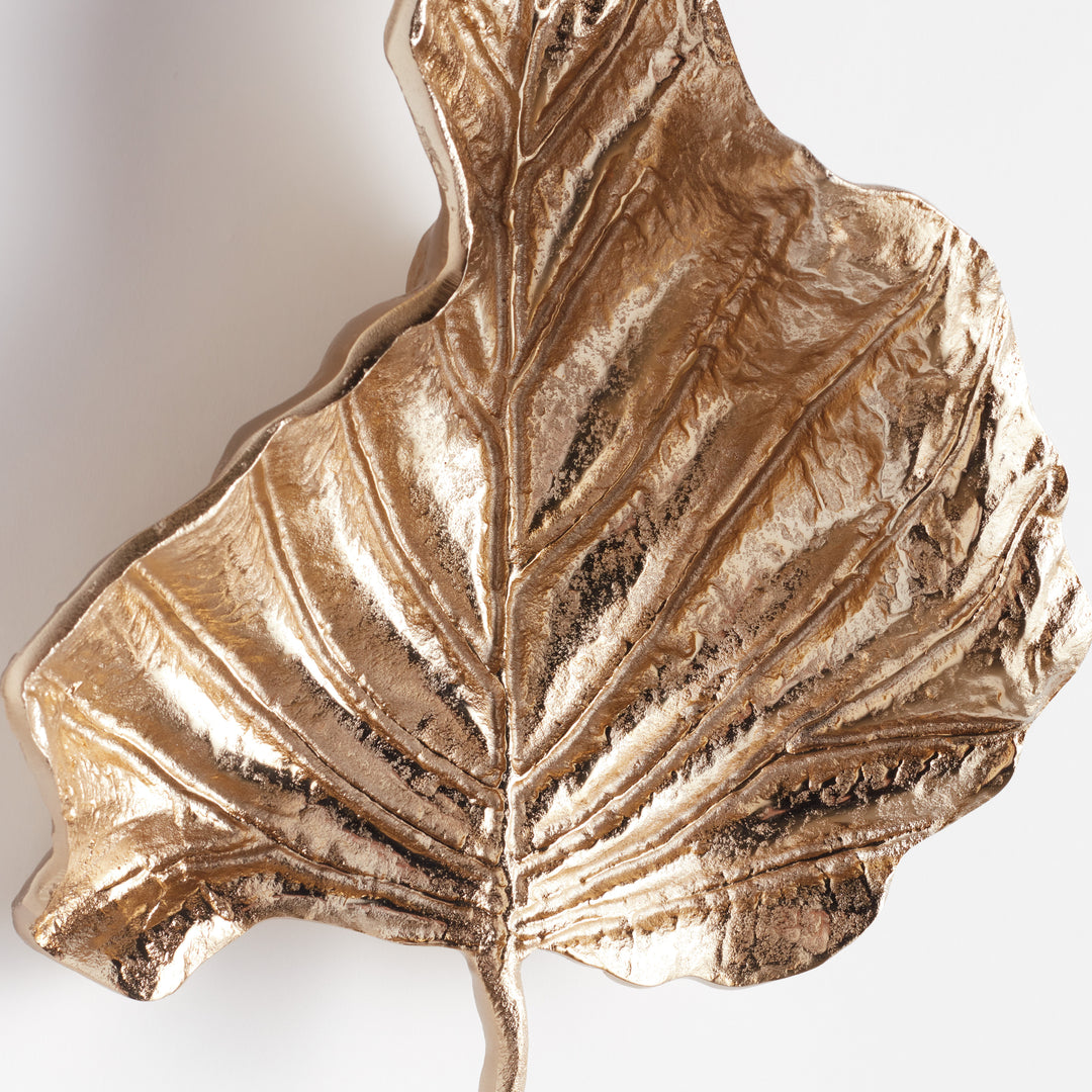 Close-up of gilded leaf wall accent revealing vein texture and soft matte-gold shimmer in cast aluminum surface – artisan botanical wall sculpture