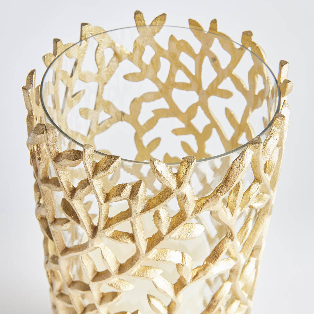 Glass votive candle holder with sculptural gold leaf overlay, blending botanical styling and refined metal craftsmanship.

