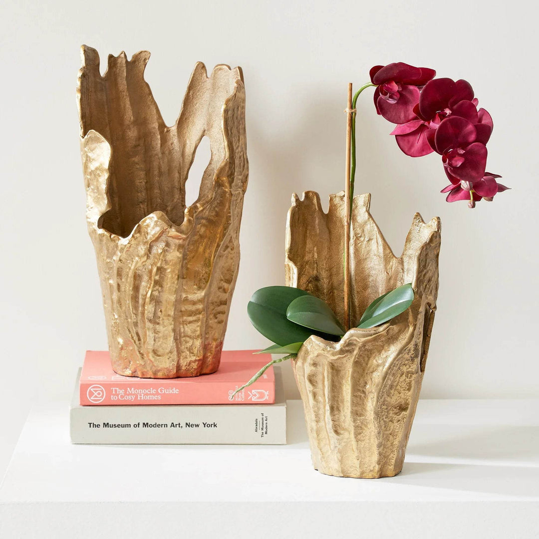 Set of two gold aluminum decorative vases with organic sculptural rims, styled with orchid on stacked books for modern interior – Organic Modern.
