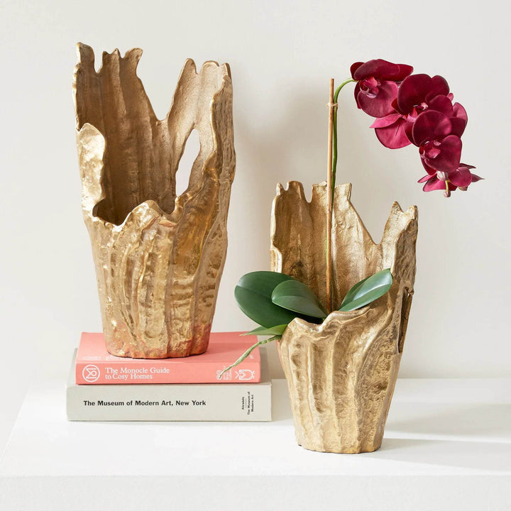 Set of two gold aluminum decorative vases with organic sculptural rims, styled with orchid on stacked books for modern interior – Organic Modern.