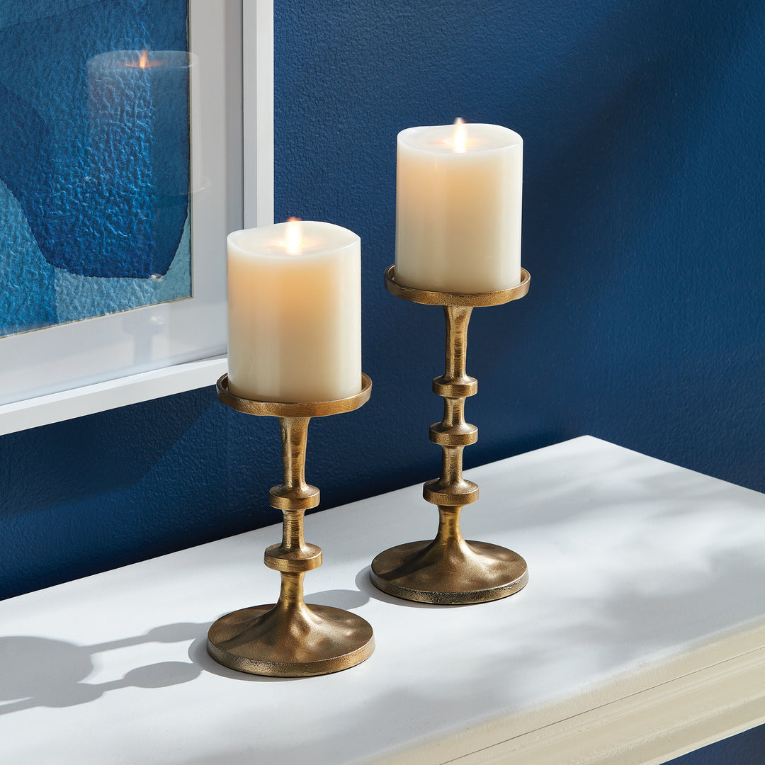 Gold aluminum pillar candle holders styled on a tabletop with elevated sculptural silhouette – Transitional