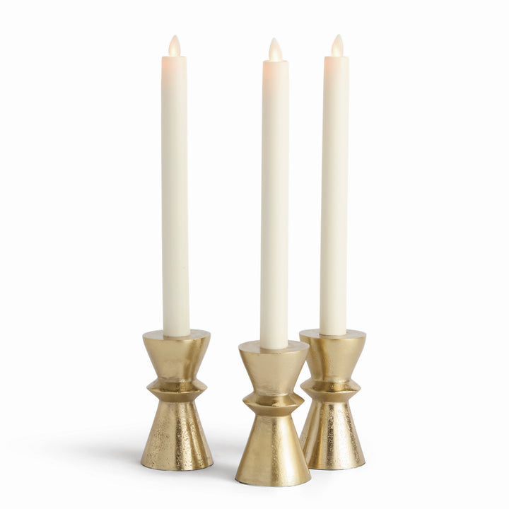 Set of three gold aluminum taper candle holders with hourglass bases, shown with ivory tapers in upright display – Modern Industrial
