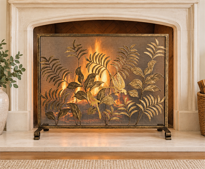Gold bird and leaf fireplace screen shown before a lit fireplace, framed by a pale stone surround with a hearth | Traditional