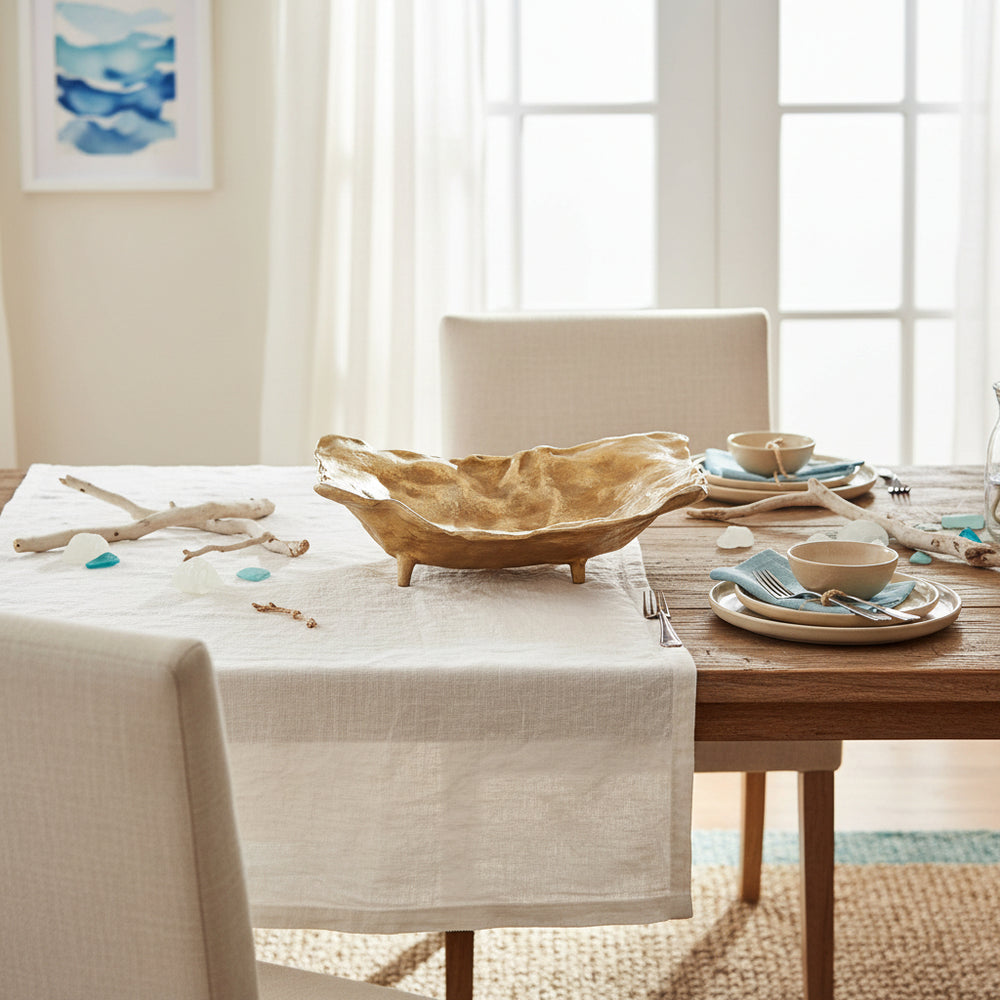 Gold cast aluminum decorative tray styled as a dining table centerpiece with plates and neutral linens in a bright interior setting