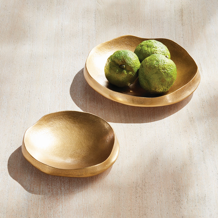 Two gold decorative bowls on pale wood, with green decorative objects in the larger bowl and a smaller empty - Modern Organic
