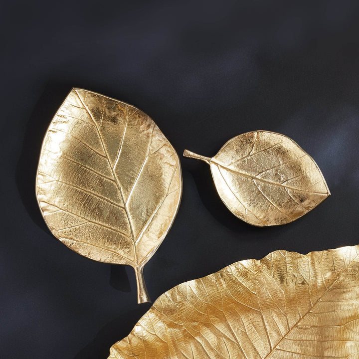 Top-down view of gold leaf trays on dark surface showing natural vein detailing and asymmetrical form – Wabi-Sabi.

