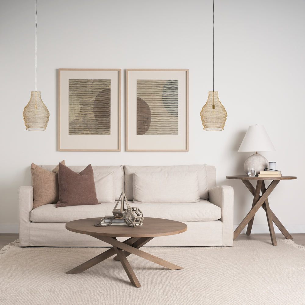 Gold mesh pendant lights beside a cream sofa, with framed abstract artwork and a round wooden coffee table – Transitional
