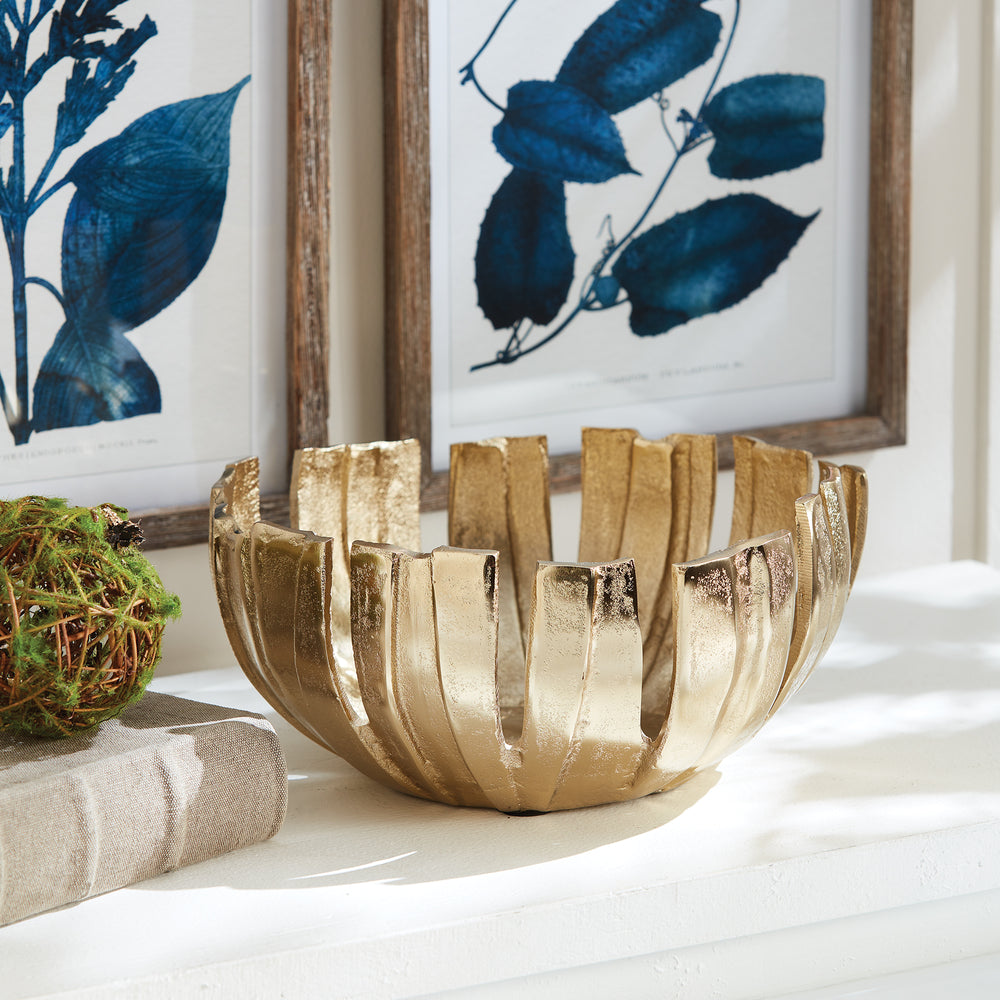 Gold decorative metal bowl styled on console table with artwork, modern centerpiece with petal design for home decor.


