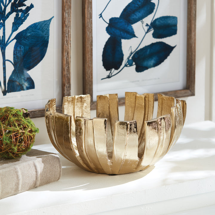 Gold decorative metal bowl styled on console table with artwork, modern centerpiece with petal design for home decor.

