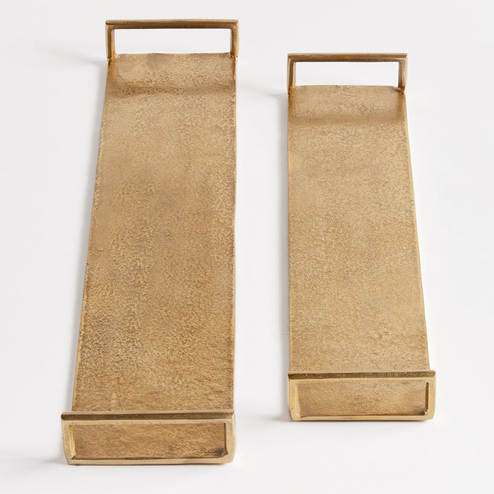Two narrow gold cast aluminum decorative trays shown from above with textured surfaces and open end handles – Transitional.