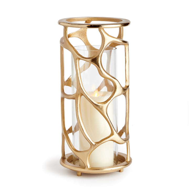Angled view of gold sculptural hurricane candle holder featuring an organic cast aluminum frame and glass insert, modern candle holder
