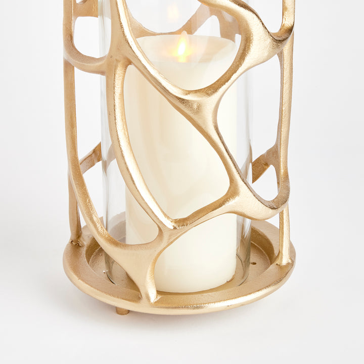 Close-up detail of gold sculptural hurricane candle holder showcasing the organic cast aluminum frame and glass insert, modern candle holder