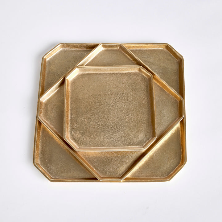 Three gold square cast aluminum serving trays nested together to show graduated sizes and geometric shape, Transitional style