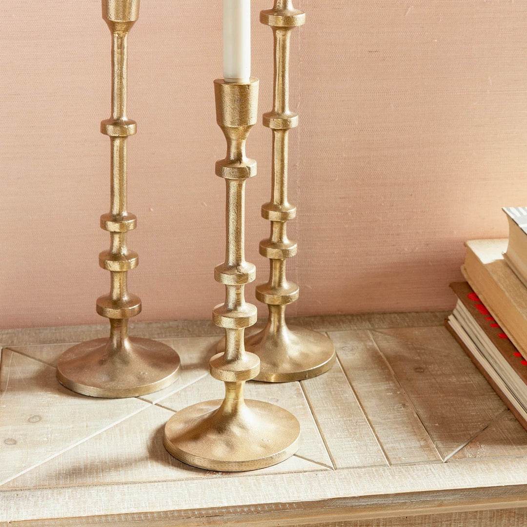 Detailed close-up of gold taper candle holder with hammered round base and notched stem design – Modern.