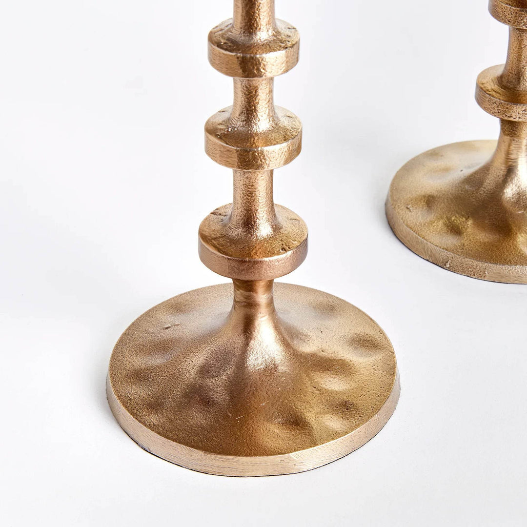 Cluster of gold taper candle holder bases with hammered texture and round supportive form – Modern.