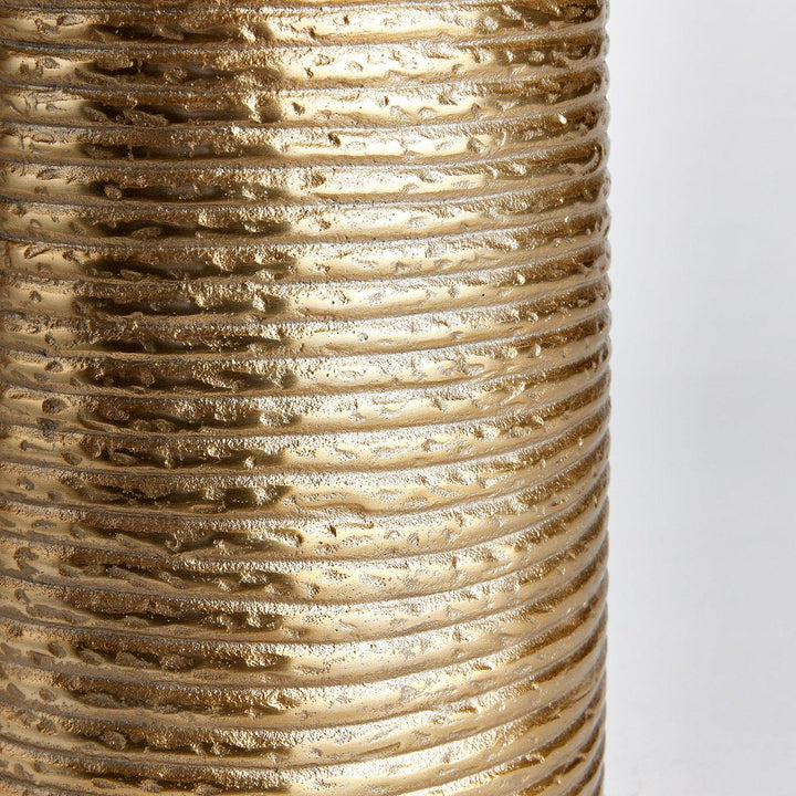 Closeup of banded texture on gold aluminum vase, highlighting horizontal ridges and warm finish

