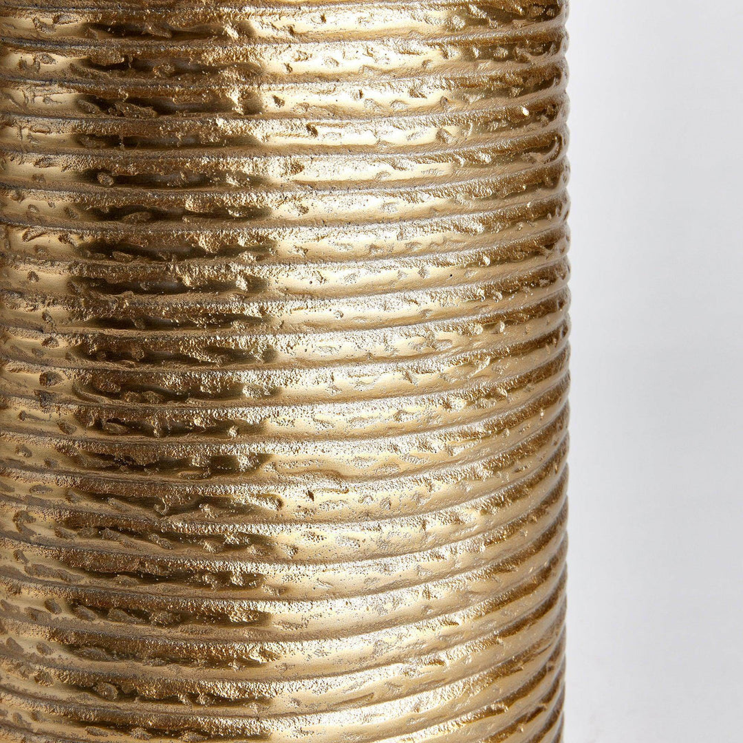 Closeup of banded texture on gold aluminum vase, highlighting horizontal ridges and warm finish


