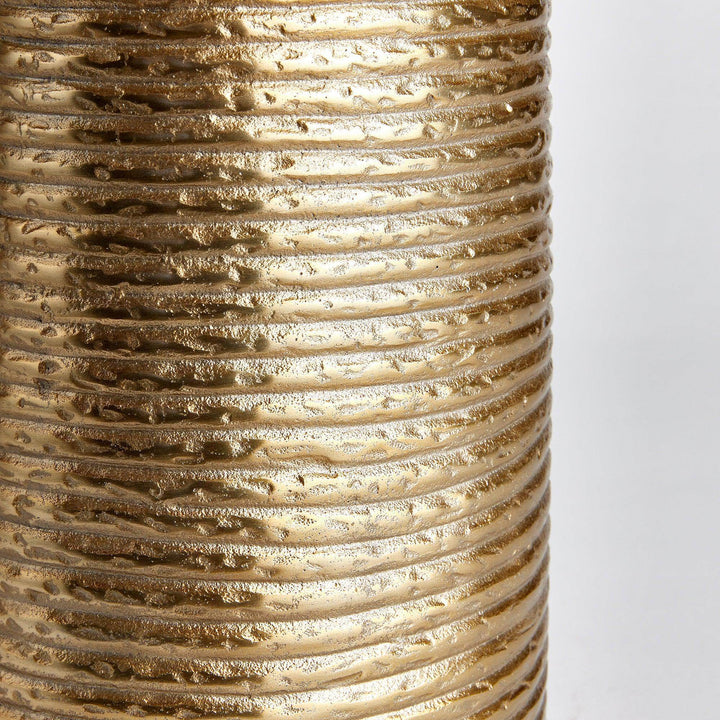 Closeup of banded texture on gold aluminum vase, highlighting horizontal ridges and warm finish

