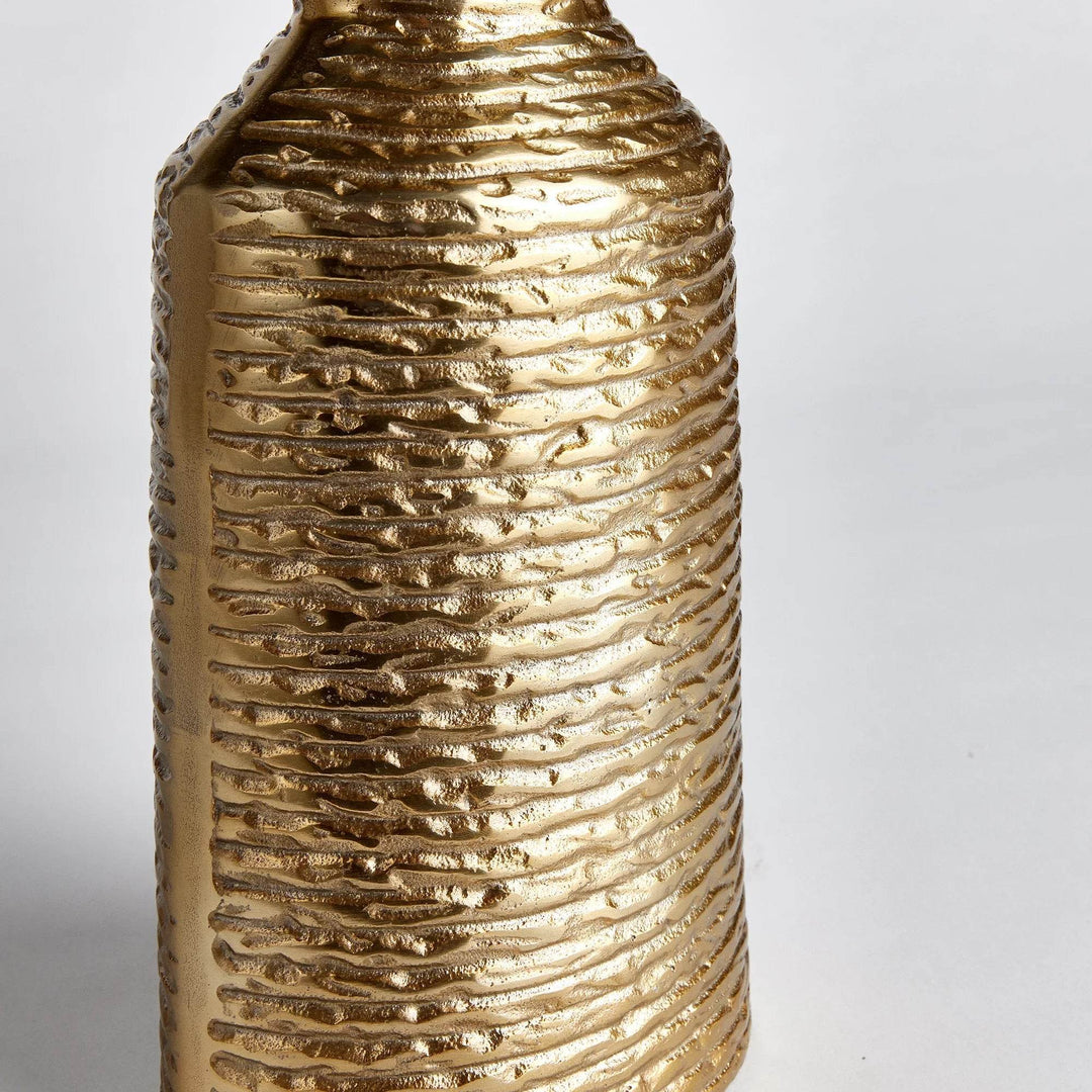 Closeup of banded texture on small gold aluminum vase, showing horizontal ridges and metallic surface

