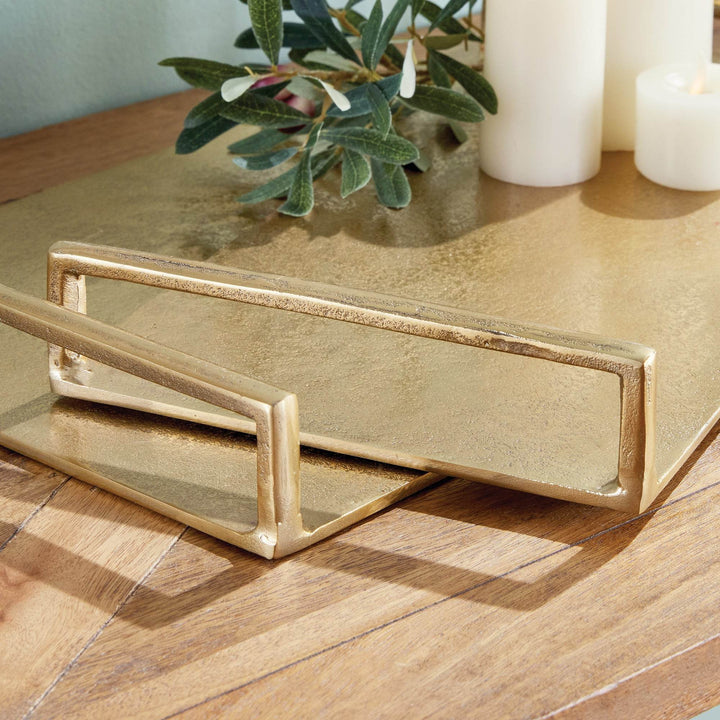 Close-up of rectangular handle on gold textured decorative tray, cast aluminum build with tactile surface – Transitional.