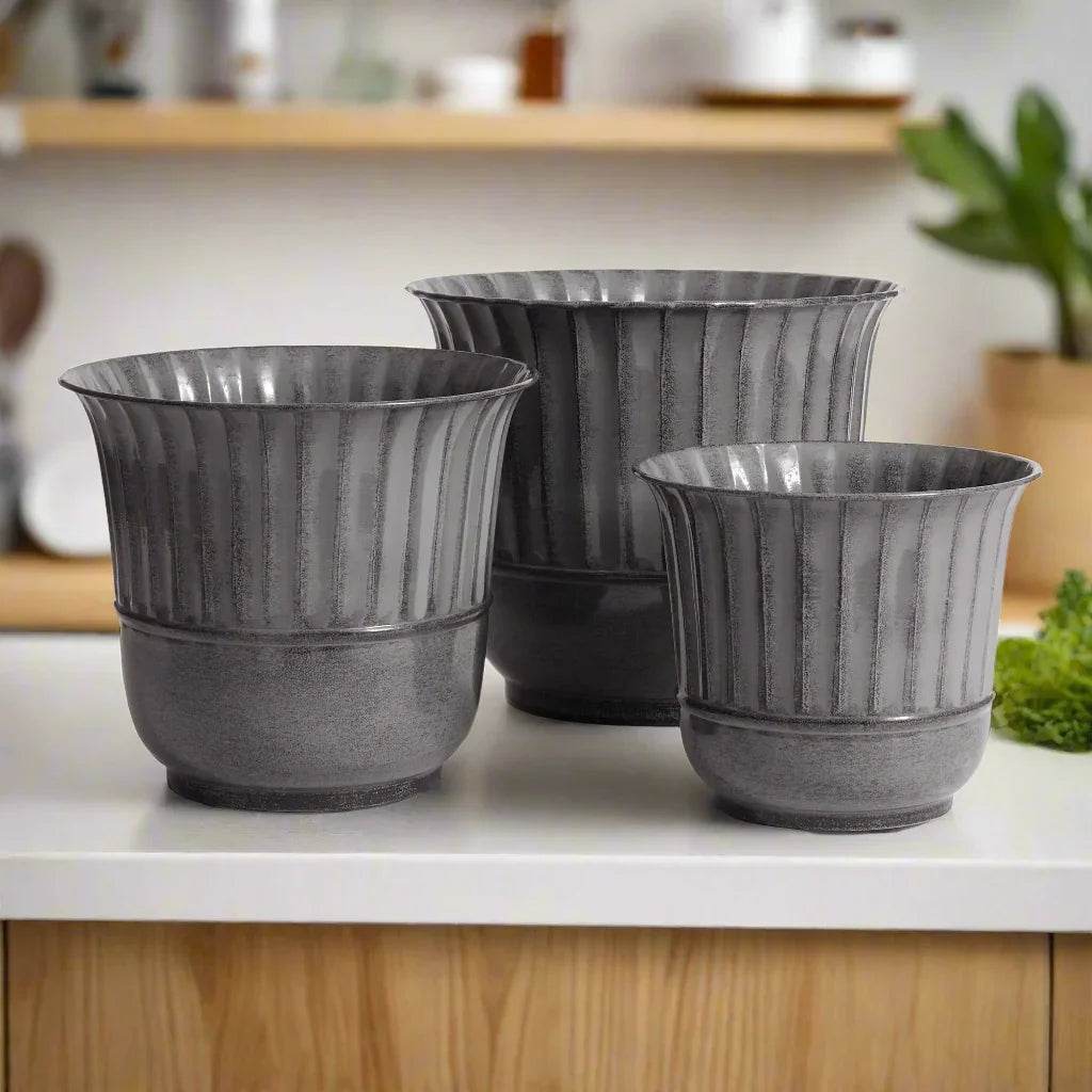 Three modern gray planters styled on a wood counter with ceramic accents