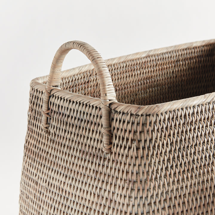 Detail of a graywash rattan basket showing the wrapped loop handle, thick woven rim and tightly woven sides, Transitional