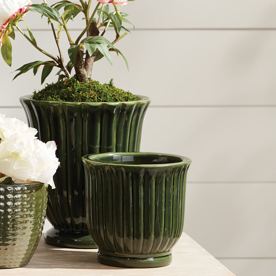 Green fluted ceramic planter pots with reactive glaze finish styled on a covered porch with layered greenery – Modern Organic style.