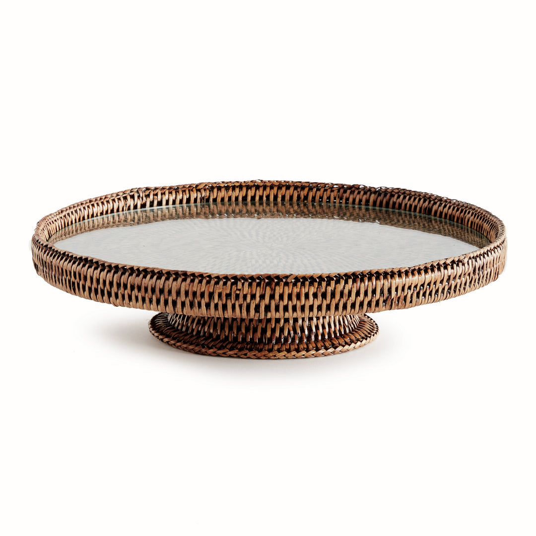 Hadley warm brown pedestal stand with a round glass insert, woven rim and low circular base on a white background. Coastal