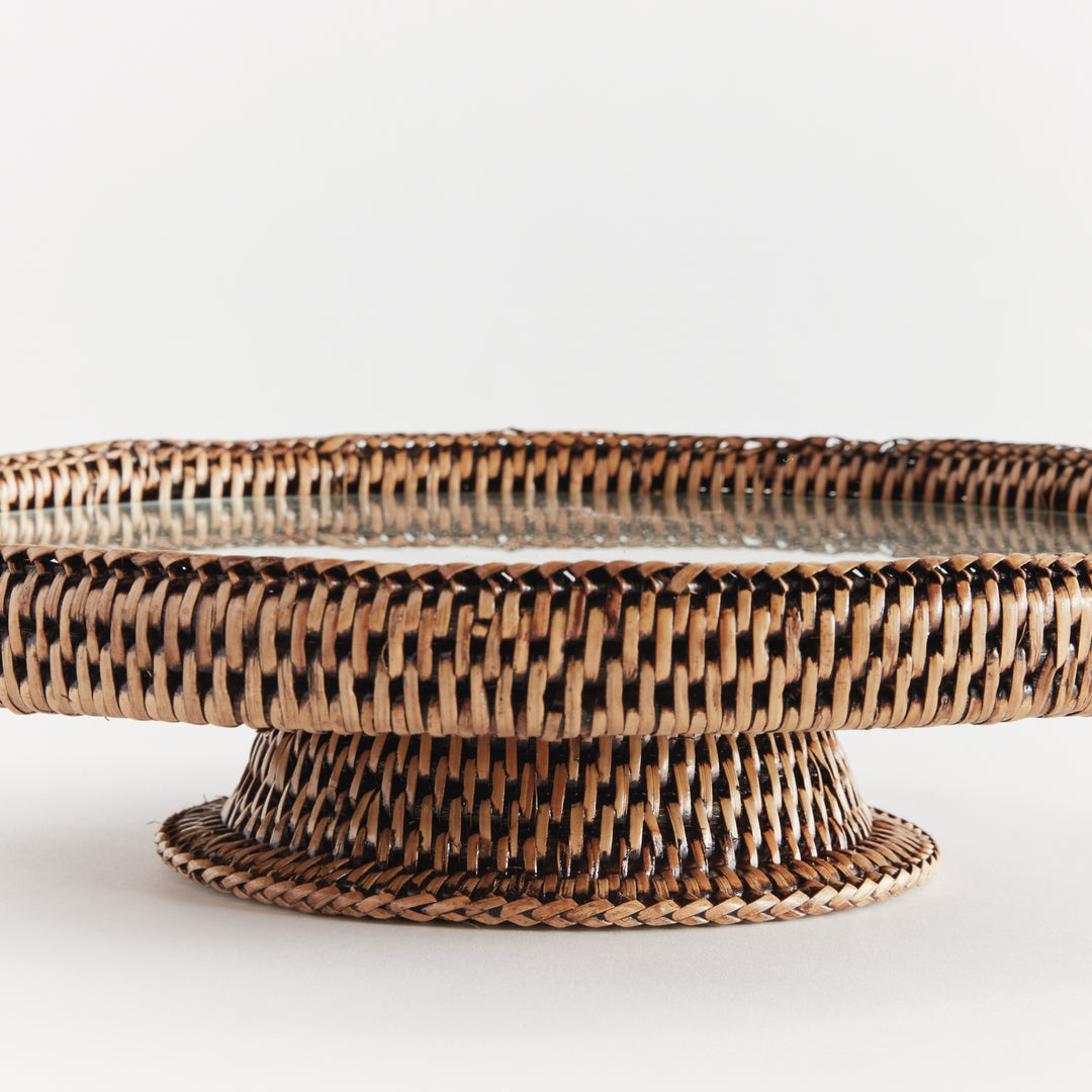 Close view of Hadley warm brown rattan pedestal stand showing the wrapped rim, clear glass insert and woven base. Coastal