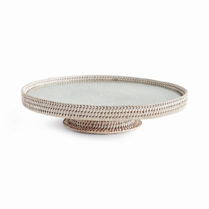 Hadley whitewash pedestal stand with a round glass insert, woven rim and low circular base on a white background. Coastal