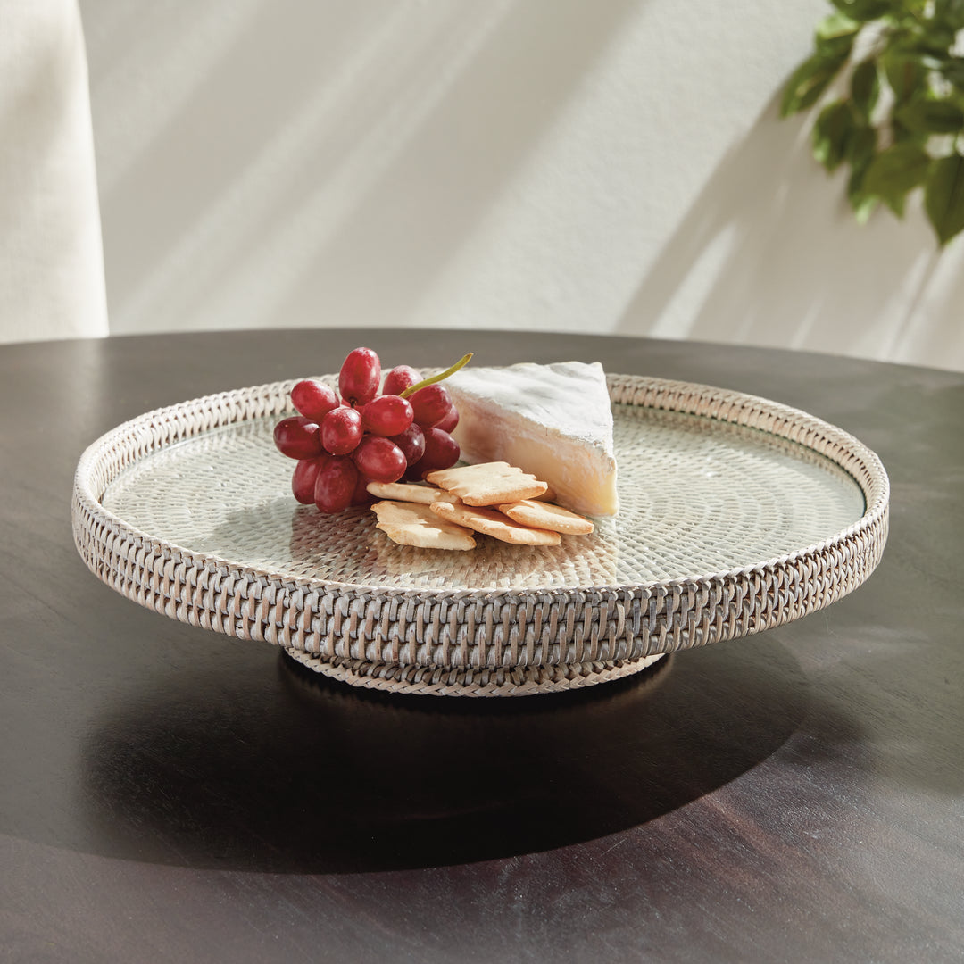 Hadley whitewash rattan stand with glass insert styled with grapes, cheese and crackers on a dark tabletop indoors. Coastal