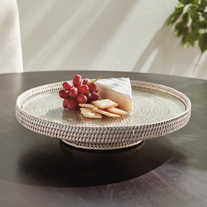 Hadley whitewash rattan stand with glass insert styled with grapes, cheese and crackers on a dark tabletop indoors. Coastal