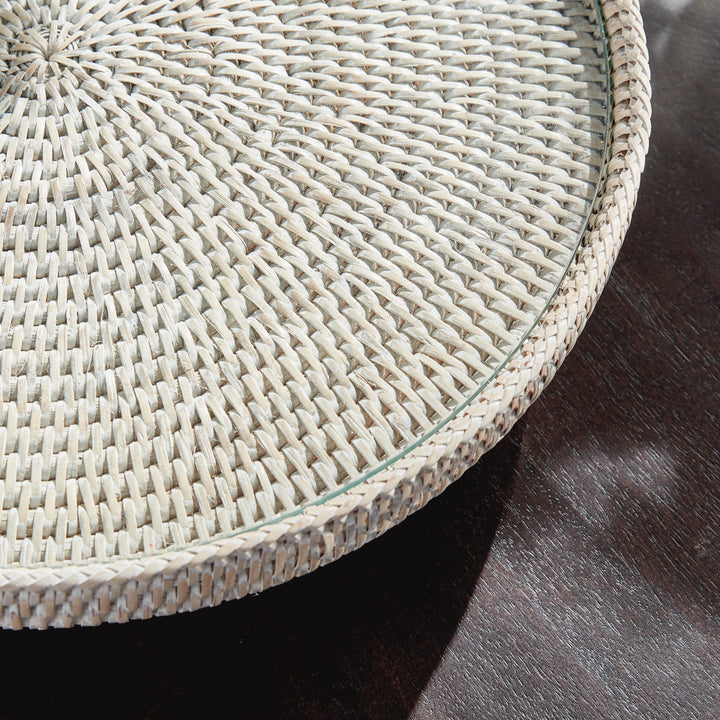 Close view of Hadley whitewash stand showing the clear glass edge and woven rattan rim above a dark wooden table. Coastal